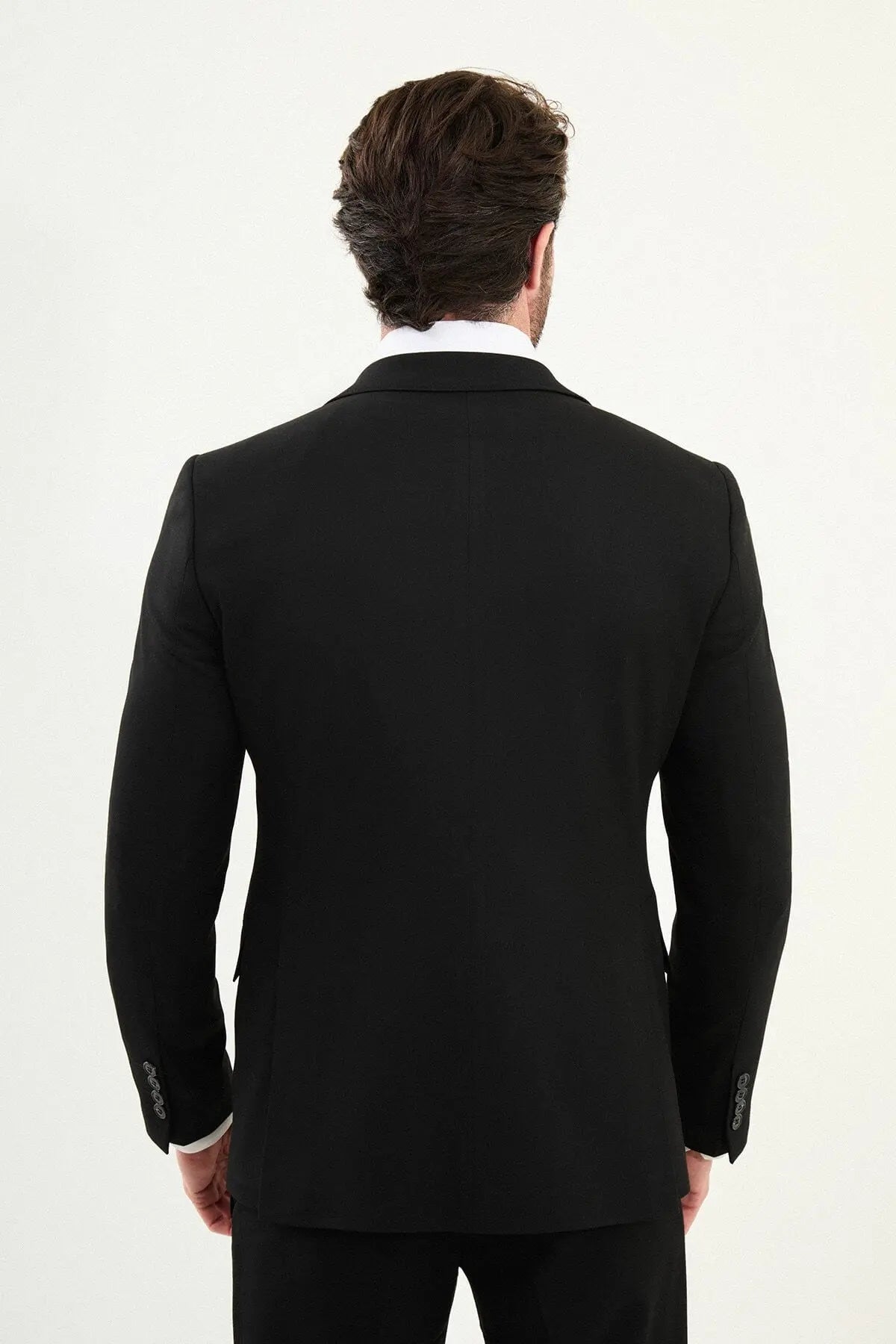 Men’s matte black slim-fit three-piece wool-blend winter suit with single-breasted jacket, notch lapels with AMF stitching, high-cut five-button waistcoat, tapered trousers, and black origami lapel pin.