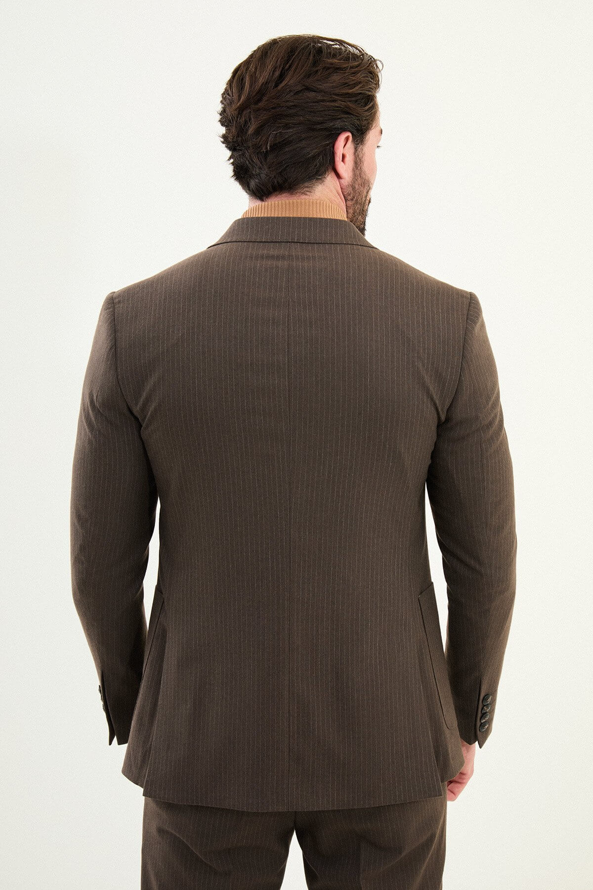 Men’s light brown slim-fit mono-collar (mandarin collar) winter suit with minimalist single-breasted jacket, matte micro-texture active-recovery fabric, styled with a camel turtleneck for tonal dressing.