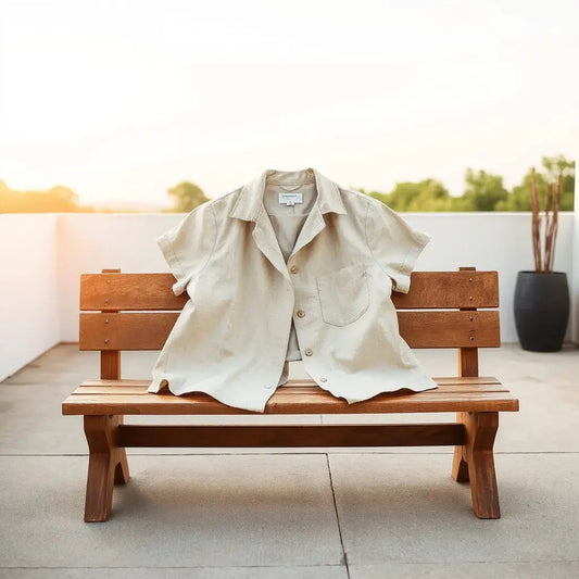 Light beige linen jacket draped on a bench with visible breathable fabric texture in warm sunlight