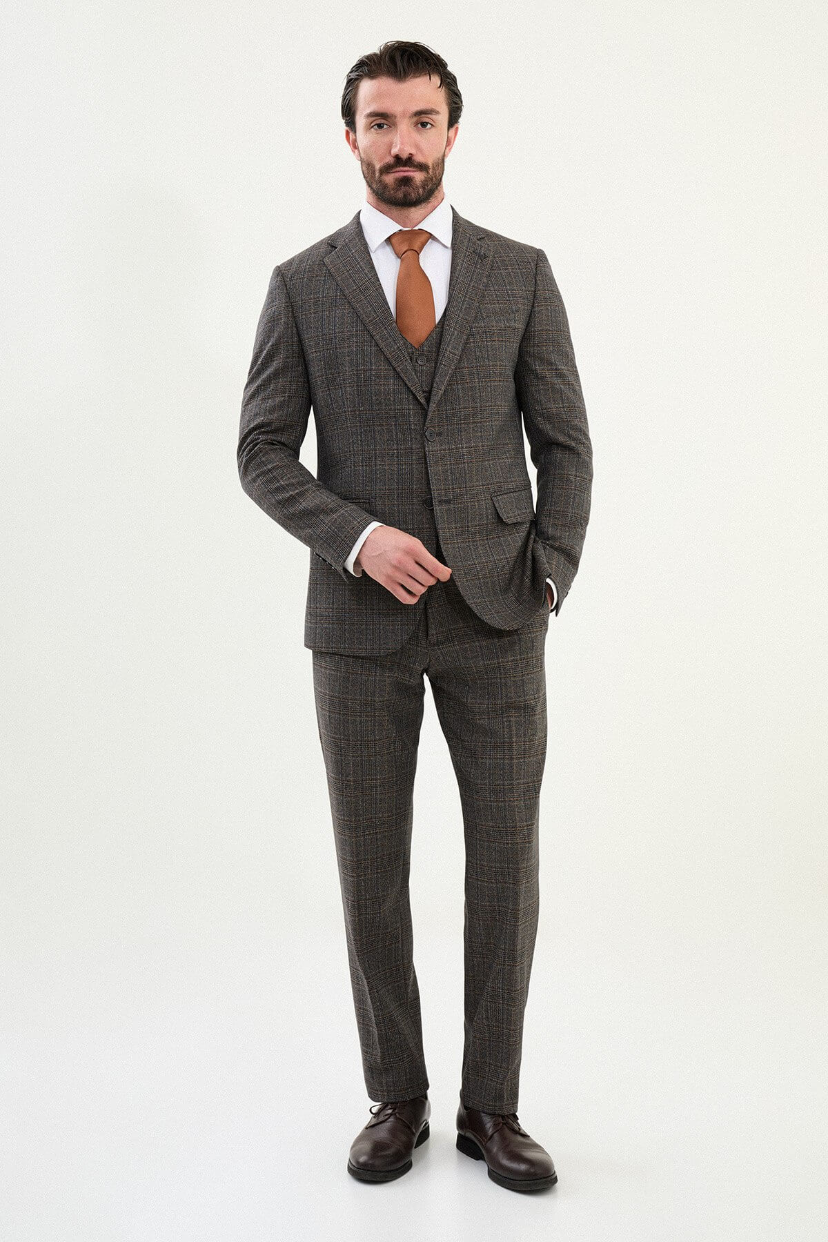 Men’s brown glen plaid slim-fit three-piece wool-blend suit with single-breasted two-button jacket, notch lapels, patch pockets, five-button waistcoat, tapered trousers, barchetta chest pocket, and black origami lapel pin.