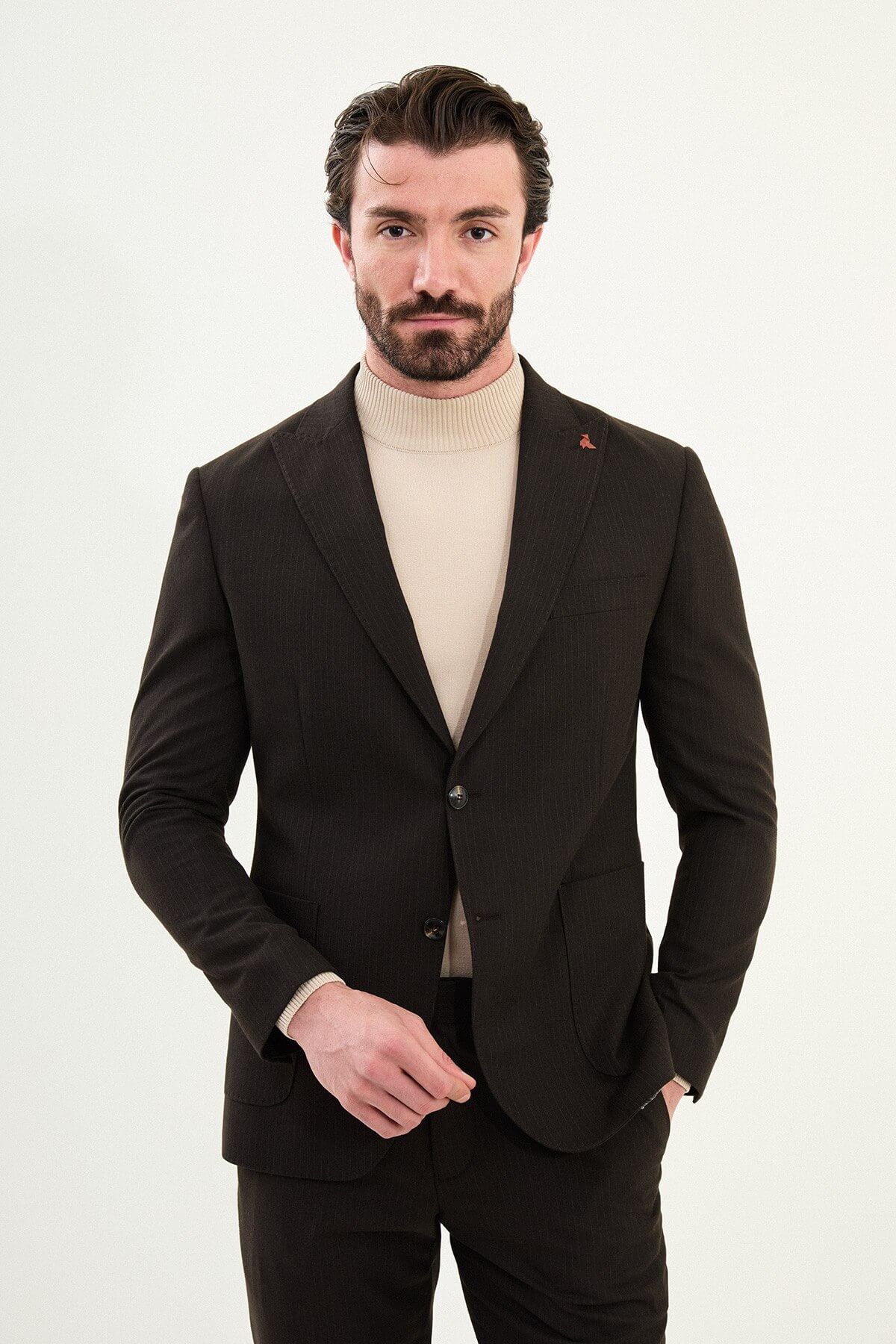 Men’s deep brown slim-fit mono-collar (mandarin collar) performance suit with single-breasted jacket, patch pockets, matte micro-texture fabric, styled with a cream turtleneck.