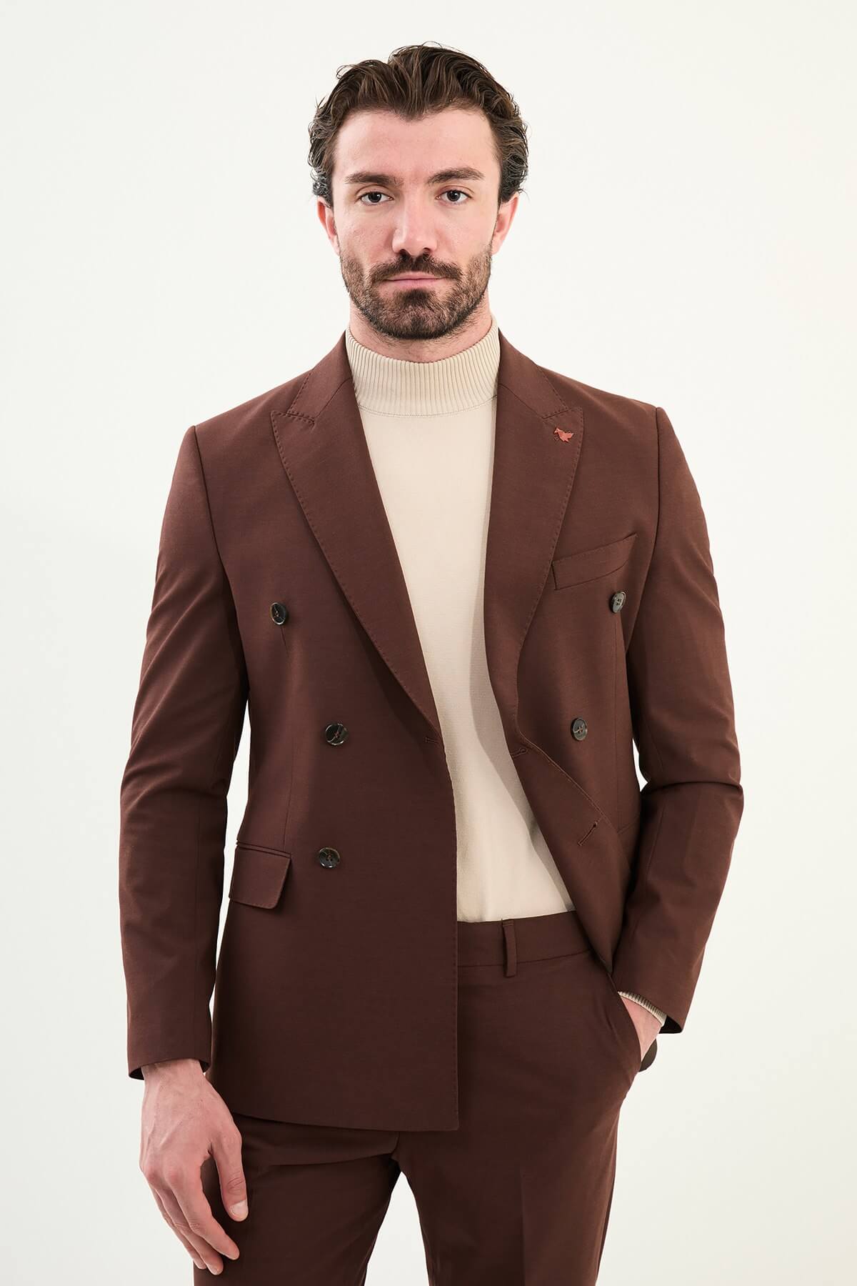 Men’s deep chocolate brown slim-fit double-breasted 6x2 suit with peak lapels, cotton-wool-viscose blend with stretch, designed for breathable comfort and wrinkle-resistant wear, styled with a cream turtleneck.