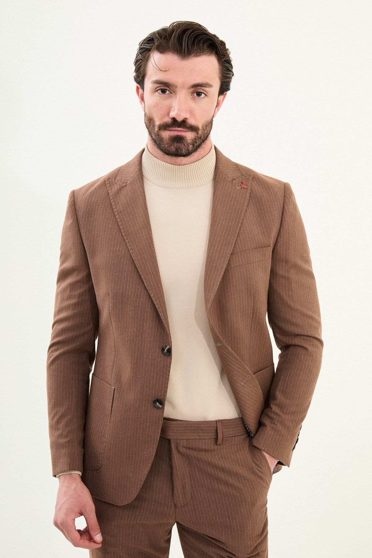 Men’s camel slim-fit mono-collar suit with pointed minimalist collar, matte micro-texture fabric, single-breasted jacket, and styled with a cream turtleneck for tonal winter dressing.