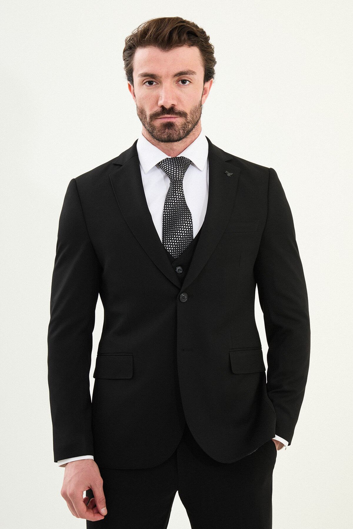 Men’s matte black slim-fit three-piece wool-blend winter suit with single-breasted jacket, notch lapels with AMF stitching, high-cut five-button waistcoat, tapered trousers, and black origami lapel pin.