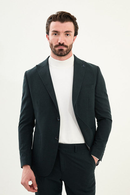 Men’s dark green slim-fit mono-collar (mandarin collar) suit with single-breasted jacket, matte micro-texture fabric, and clean minimalist tailoring designed for turtleneck layering.