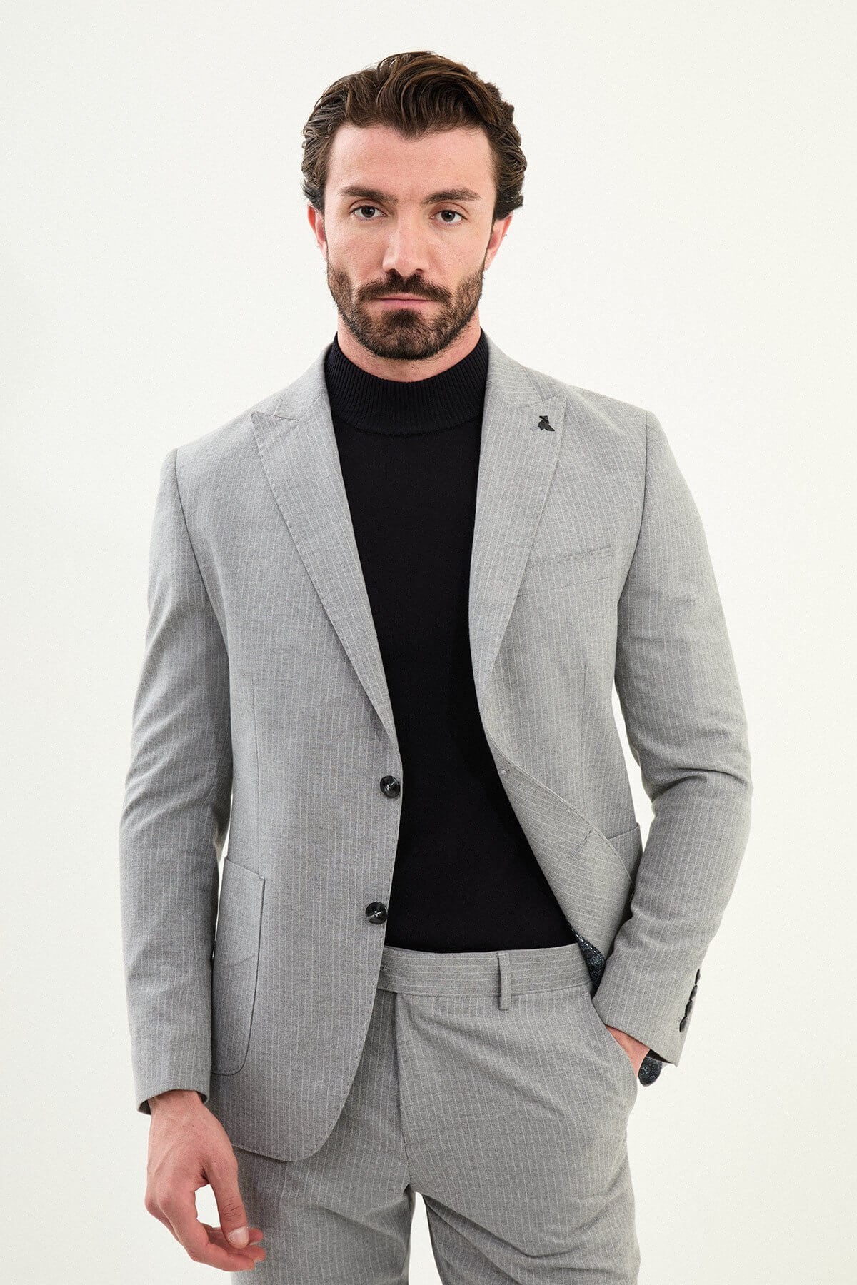Men’s gray slim-fit mono-collar (mandarin collar) performance suit with 2-button single-breasted jacket, minimalist patch pockets, matte micro-texture fabric, styled with a black turtleneck.