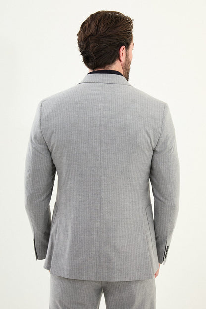 Men’s gray slim-fit mono-collar (mandarin collar) performance suit with 2-button single-breasted jacket, minimalist patch pockets, matte micro-texture fabric, styled with a black turtleneck.
