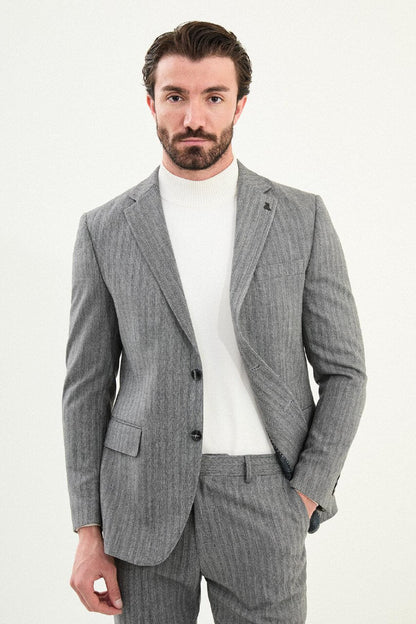 Men’s gray herringbone slim-fit single-breasted suit with structured shoulders and tailored waist, high-wool blend fabric with stretch, styled with a light gray fine-gauge turtleneck for winter.