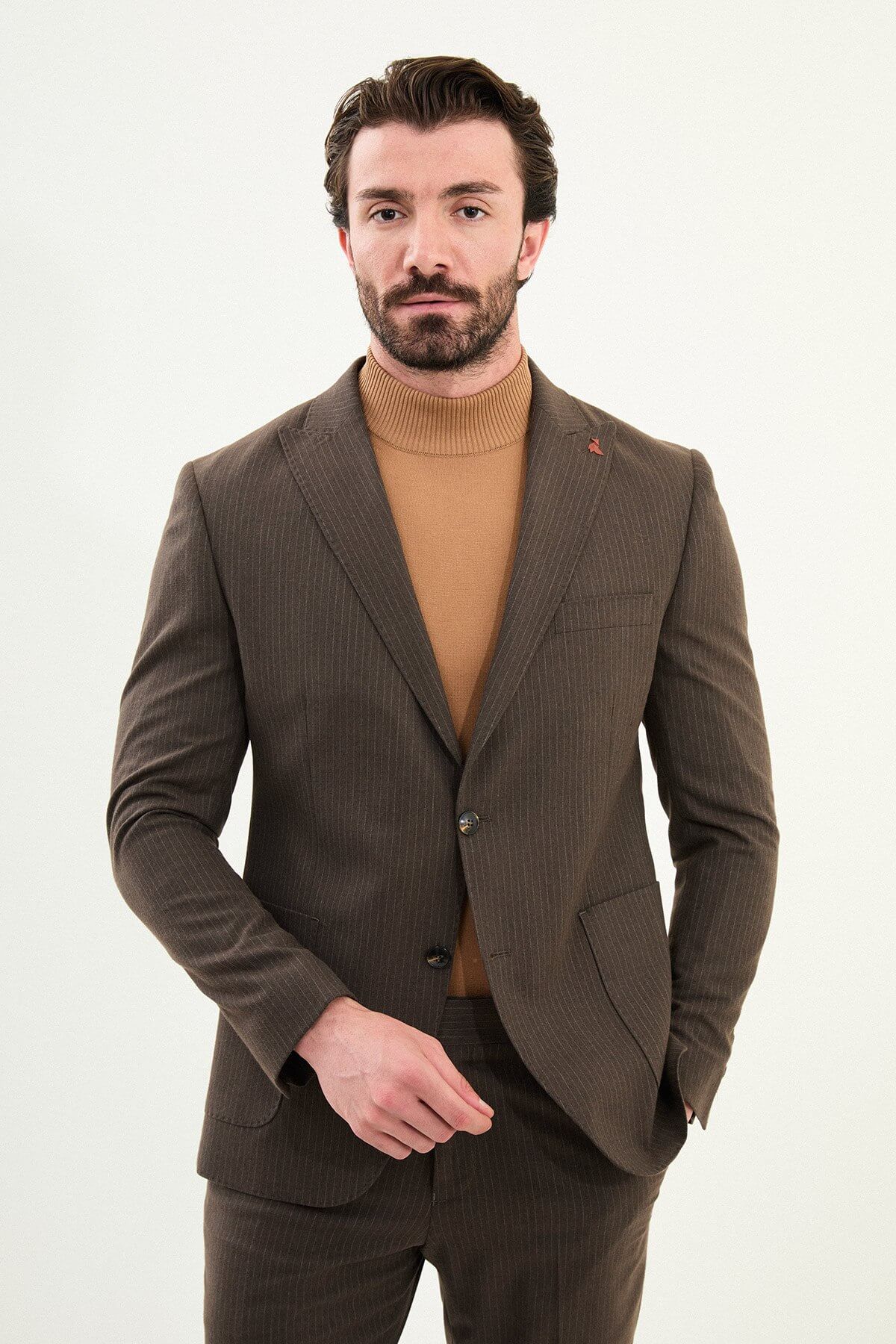Men’s light brown slim-fit mono-collar (mandarin collar) winter suit with minimalist single-breasted jacket, matte micro-texture active-recovery fabric, styled with a camel turtleneck for tonal dressing.