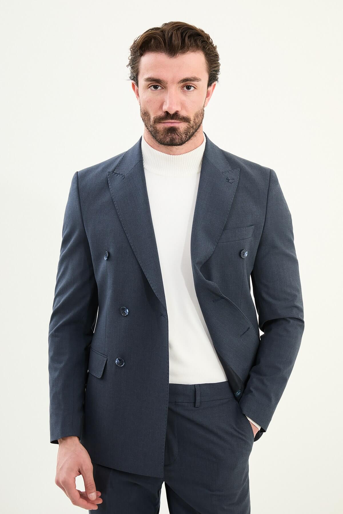 Men’s navy blue slim-fit double-breasted 6x2 suit with peak lapels, matte micro-texture finish, cotton-wool-viscose blend with stretch for wrinkle-resistant wear, styled with a white turtleneck.